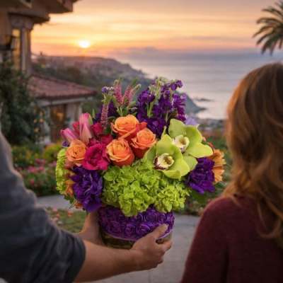 Colorful mixed bouquet in a vase held at a doorway overlooking the ocean