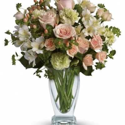 Pink roses and white flowers arranged in a clear glass vase