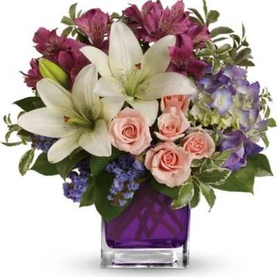 Bouquet of white lilies, pink roses, and purple flowers in a purple vase