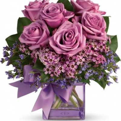 Lavender roses in a square glass vase with a purple ribbon