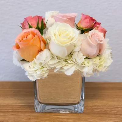 Mixed roses and white hydrangeas in a square glass vase