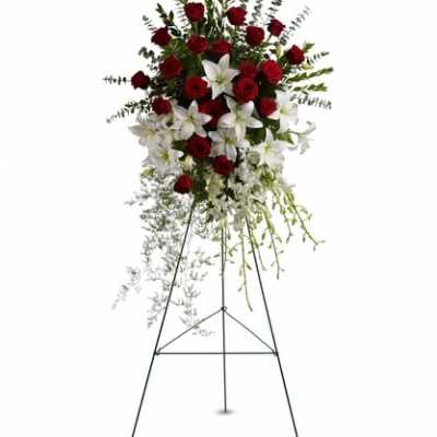 Standing floral spray with red roses and white lilies on an easel
