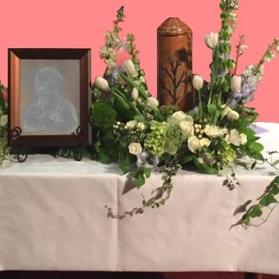 Floral funeral display with framed portrait and tall white flower arrangements