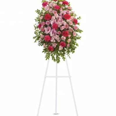 Standing floral spray of pink and red flowers on a white easel