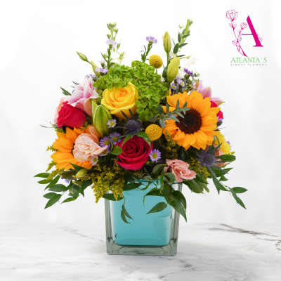 Colorful bouquet in a square glass vase with roses and sunflowers
