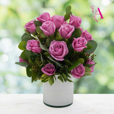 Pink roses arranged in a white vase with green foliage