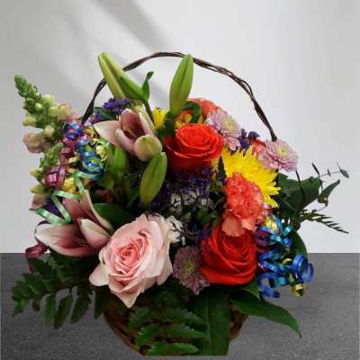 Basket arrangement of lilies, roses, carnations, and daisies with ribbon curls