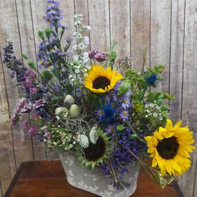 Mixed bouquet with sunflowers and purple flowers in a gray container
