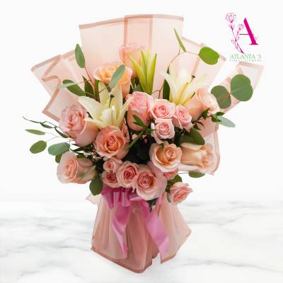 Peach roses and white lilies in pink wrapping with a ribbon