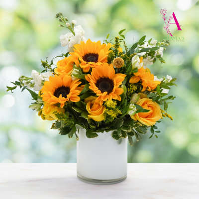 Sunflower and yellow rose arrangement in a white glass vase