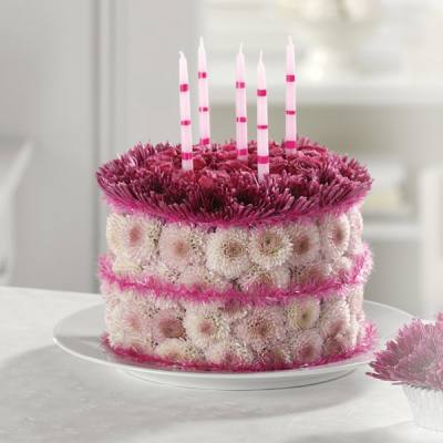 Round floral cake with pink and white flowers and striped candles