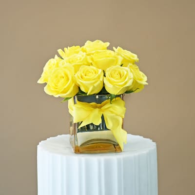 Yellow roses in a square glass vase with a yellow ribbon