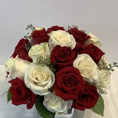 Red and white roses arranged in a clear square vase