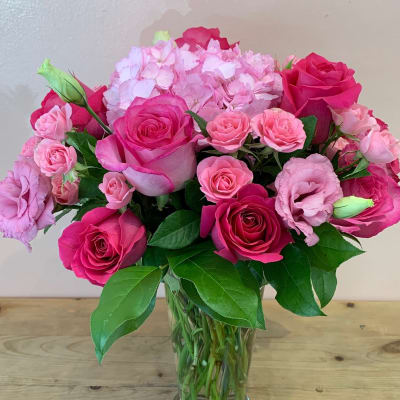 Pink roses and lisianthus arranged in a clear glass vase