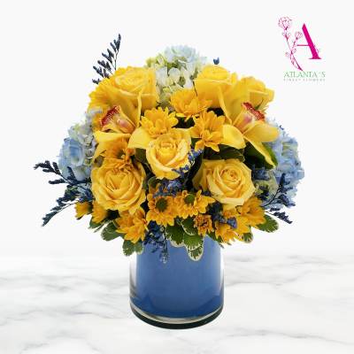 Yellow roses and orchids arranged in a blue vase