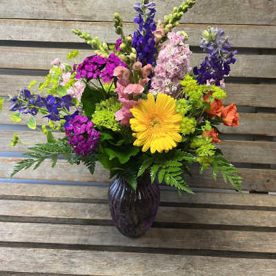 Colorful mixed flower arrangement in a dark glass vase