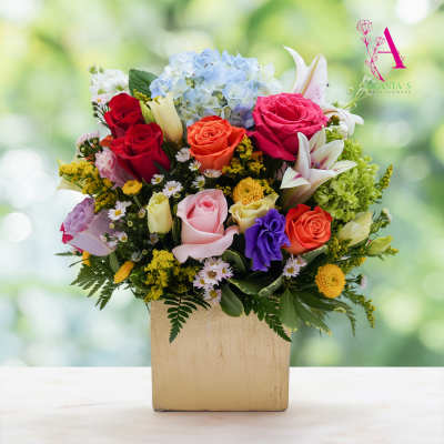 Mixed bouquet of roses, lilies, and hydrangea in a square vase