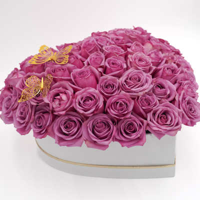 Heart-shaped box filled with pink roses and two gold butterfly decorations
