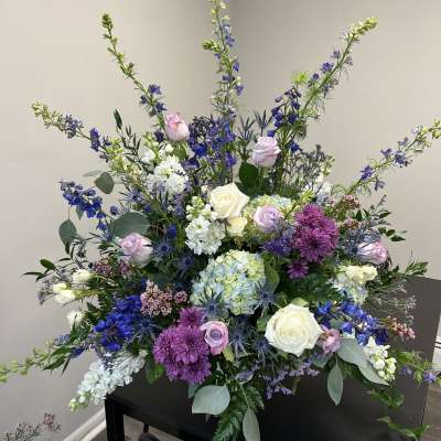 Large mixed floral arrangement with roses, hydrangeas, and purple blooms