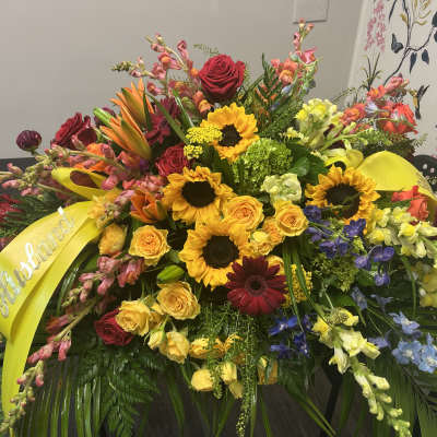 Large mixed flower spray with yellow ribbon and roses, sunflowers, and lilies