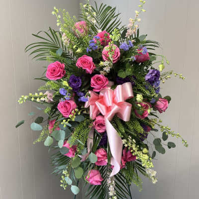 Standing floral spray with pink roses and purple blooms on an easel