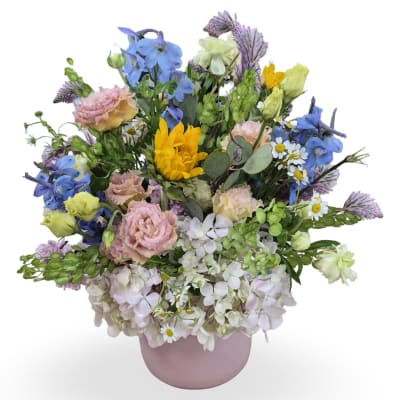 Mixed bouquet in a pink vase with blue, yellow, and pastel flowers