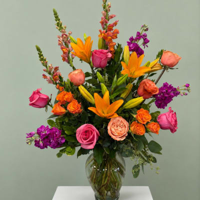 Colorful mixed bouquet in a clear glass vase with roses and lilies