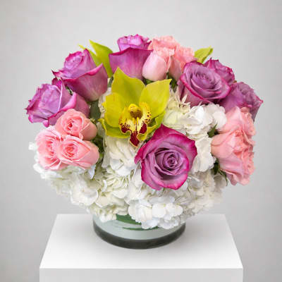 Round bouquet of pink and purple roses with white hydrangeas in a glass vase
