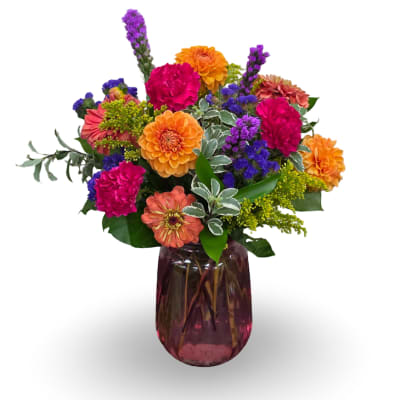 Colorful mixed flower arrangement in a purple glass vase