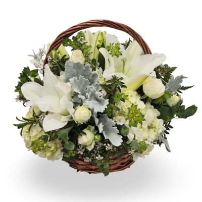 White lilies and roses arranged in a round wicker basket with handle