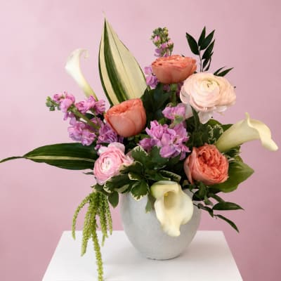 Mixed bouquet with peach, pink, and white flowers in a white vase
