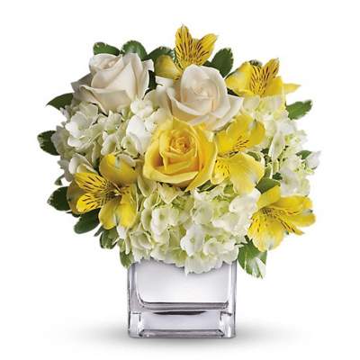 Yellow and white flower arrangement in a clear square vase