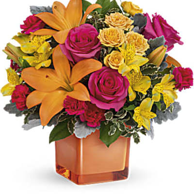 Bright bouquet of orange lilies, pink roses, and yellow flowers in an orange vase