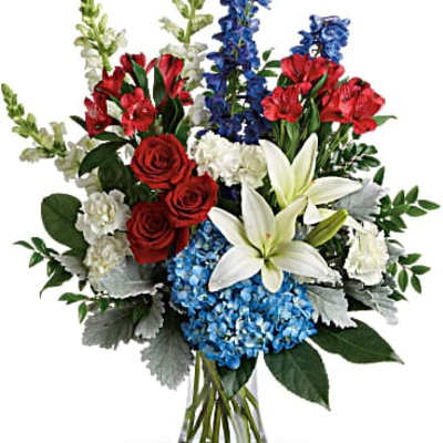 Mixed bouquet with red roses, white lilies, blue flowers, and red blooms in a glass vase