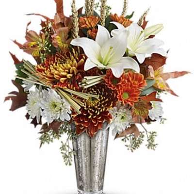 Autumn bouquet of white lilies and orange chrysanthemums in a silver vase