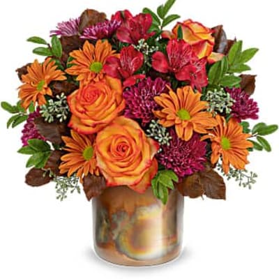 Orange roses and mixed daisies in a glass vase
