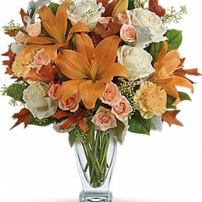 Orange lilies and white roses in a clear glass vase