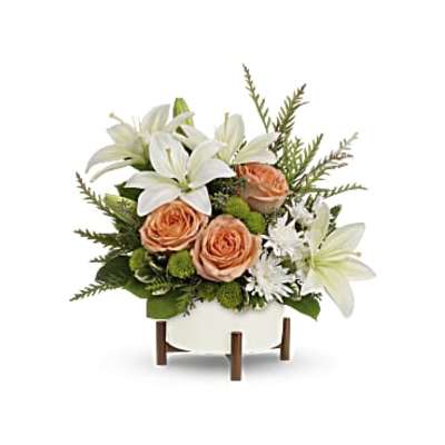 White lilies and peach roses arranged in a white container