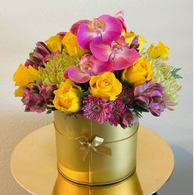 Pink orchids and yellow roses in a gold round box