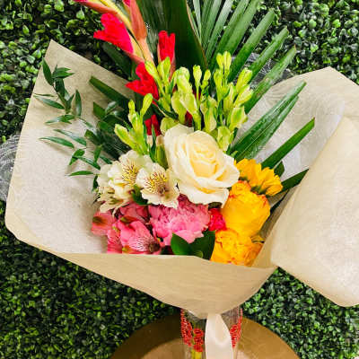 Mixed bouquet with roses, alstroemeria, and bright tropical blooms in a glass vase