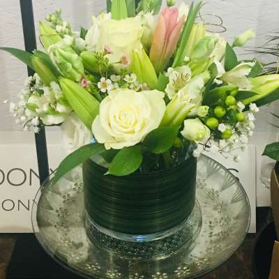 White and pale green floral arrangement in a glass vase