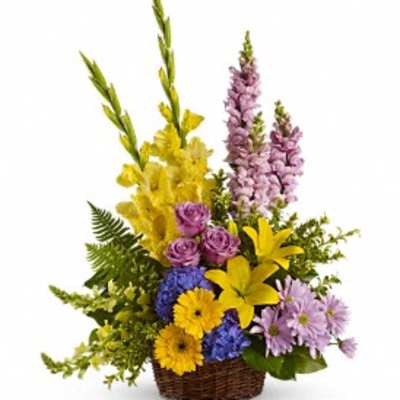 Basket arrangement with purple roses, yellow lilies, and blue flowers