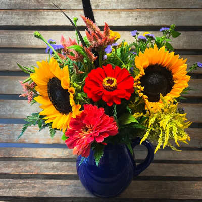 Bright mixed bouquet with sunflowers and zinnias in a blue mug