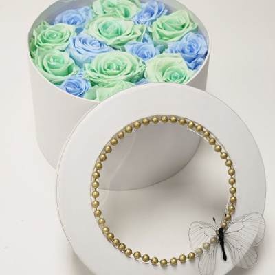 Round box of pastel roses with a gold beaded lid and butterfly accent