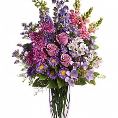 Purple and pink mixed flower arrangement in a clear vase