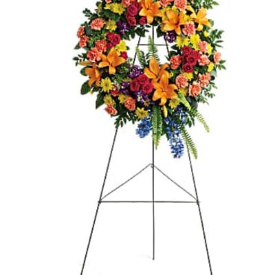 Large floral wreath on a standing easel with orange, pink, yellow, and blue flowers