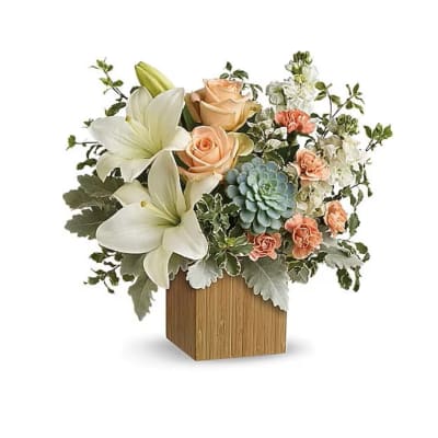 Floral arrangement with white lilies, peach roses, and a blue succulent in a wooden cube vase