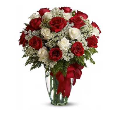 Bouquet of red and white roses in a clear glass vase with a red ribbon