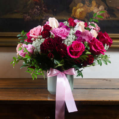 Bouquet of pink and red roses in a gray vase with a pink ribbon