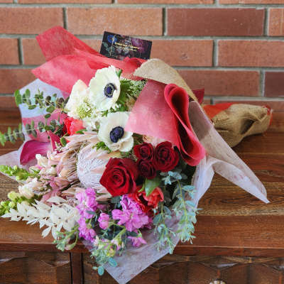 Bouquet of red and white flowers wrapped in pink paper and burlap